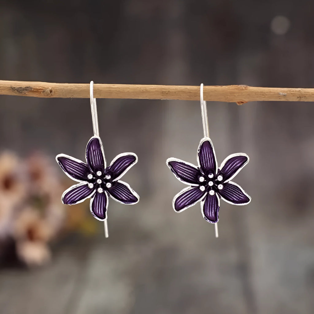 A pair of purple flower-shaped alloy stud earrings with a simple post back, shown against a plain background.