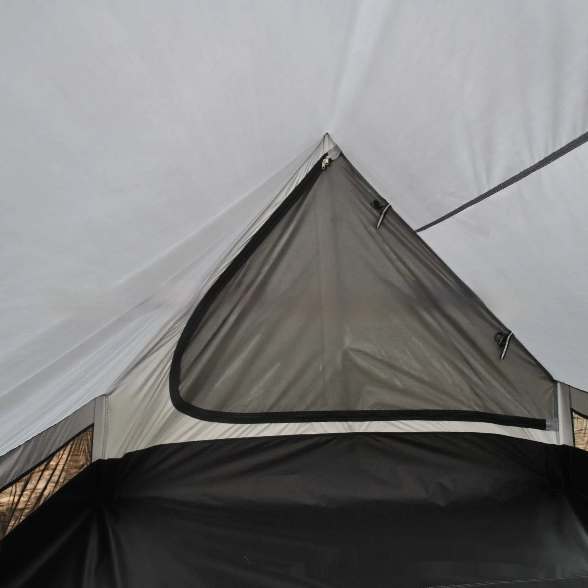 Brown ultralight A-frame hiking tent pitched with hiking poles in an outdoor setting