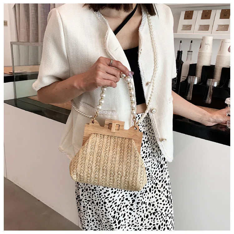 Women's woven straw shoulder bag with pearl chain strap in beige, showing internal organiser pockets.