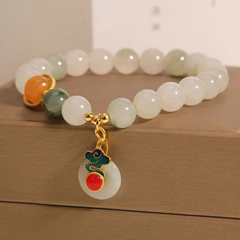 Close-up of a women's ice jade bracelet with carved Xiangyun design, pearl accents, and a jade sliding buckle.