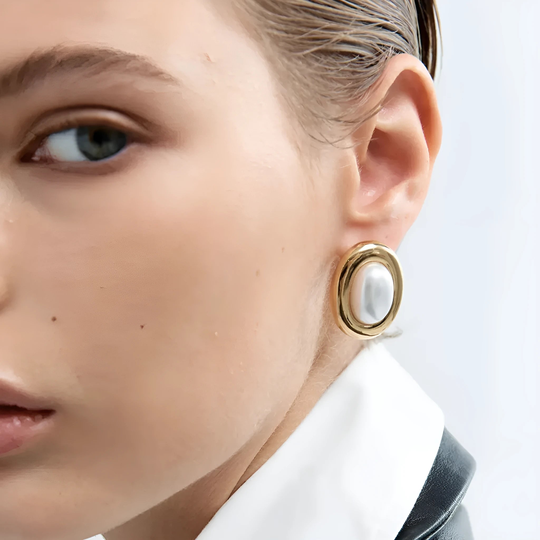 Close-up of a pair of women's stainless steel vintage pearl ear studs with a silver-toned post on a white background.