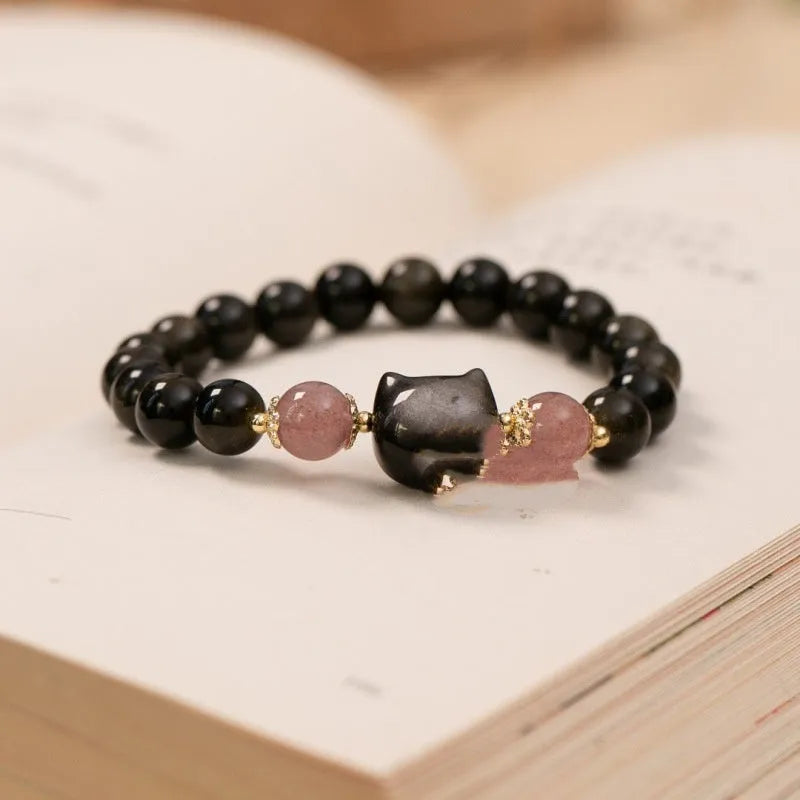 Black obsidian beaded bracelet with silver kitty cat charms on a wrist.