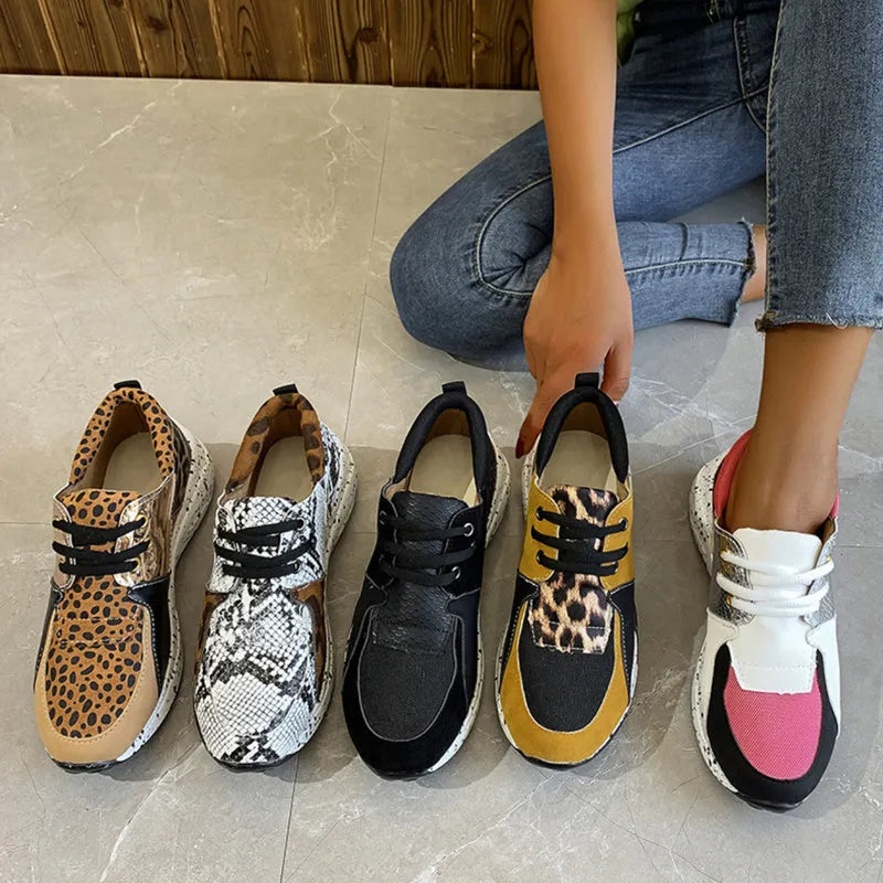 Women's black suede casual sneakers with a wedge heel on a wooden floor.