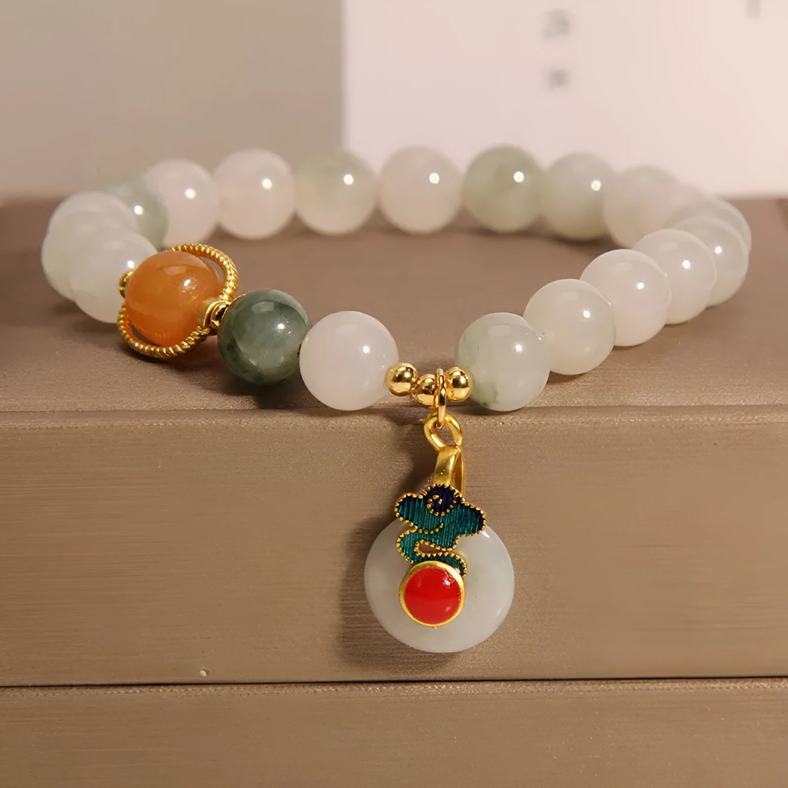 Close-up of a women's ice jade bracelet with carved Xiangyun design, pearl accents, and a jade sliding buckle.