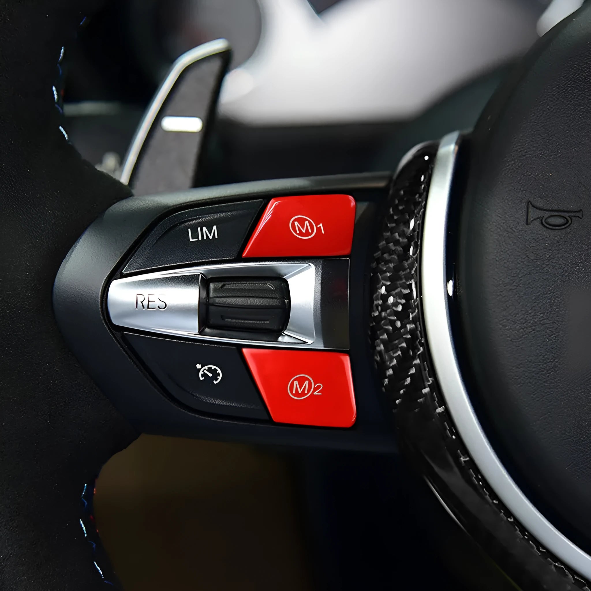 Pair of red and blue BMW M1 M2 steering wheel mode buttons on a dark background.