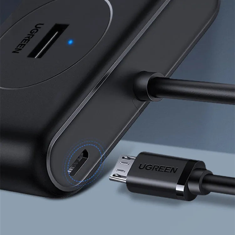 Deep black USB splitter hub with four ports, ABS plastic shell, and indicator light on desk