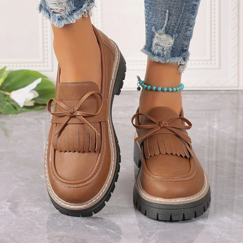 Black women's loafers with a tassel and bowknot decoration on the front, showing a round toe and low-top design.