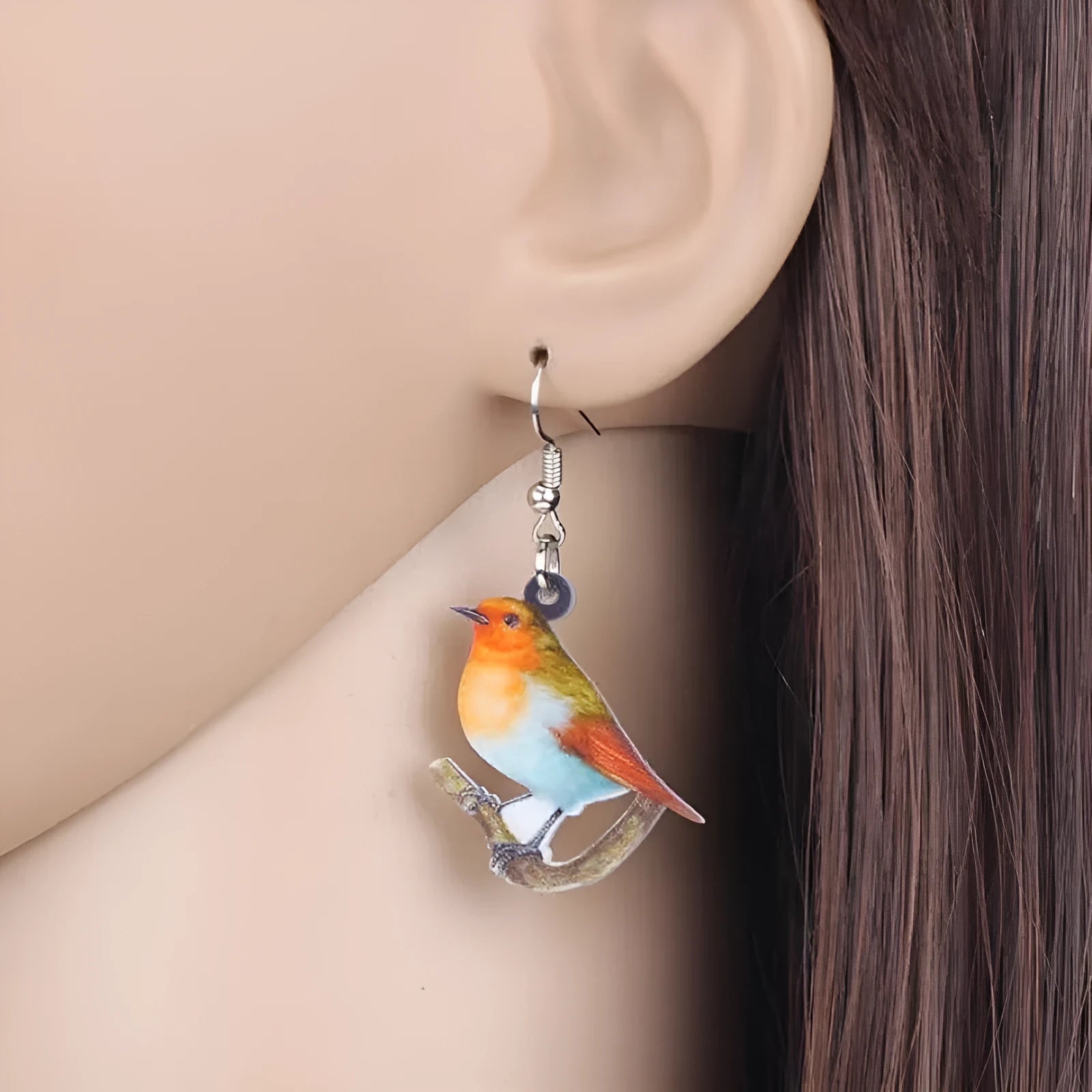 Close-up of blue titmouse and geometric zodiac pendant earrings made from printed acrylic.