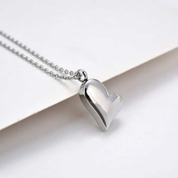 Silver curved peach heart stainless steel pendant necklace on display