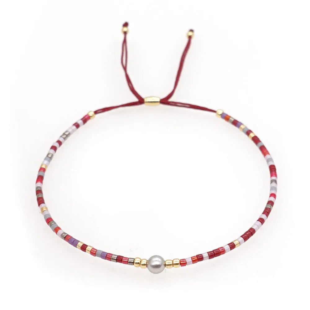 Close-up of a woman's handmade Bohemian bracelet with colourful geometric glass and glaze beads.