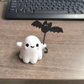 Miniature ghost walking dog statue holding a bat, a small resin Halloween ornament.