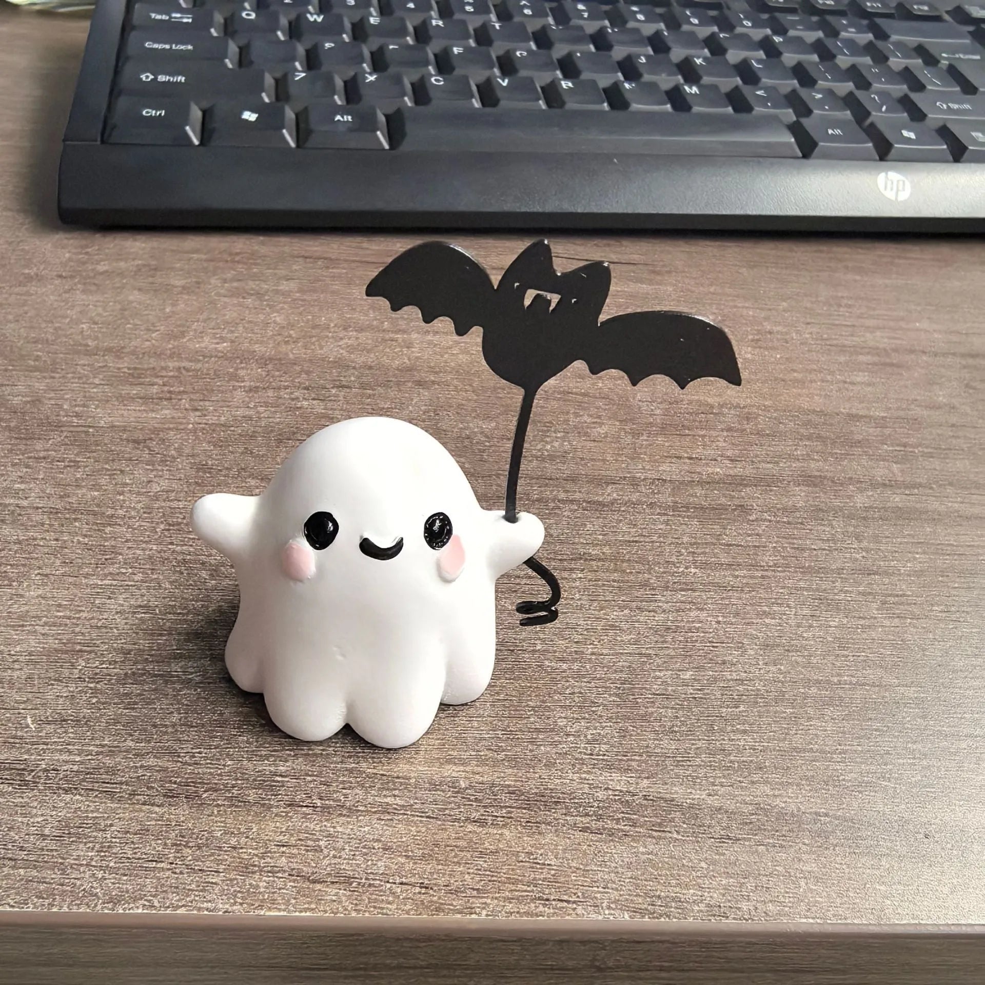Miniature ghost walking dog statue holding a bat, a small resin Halloween ornament.