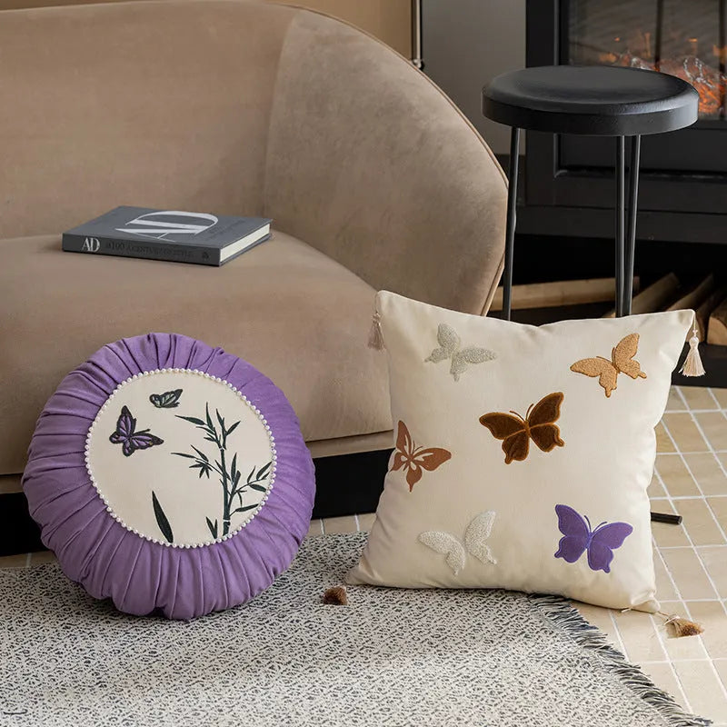 Square beige cushion with embroidered Chinese-style butterfly design.