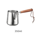 Stainless steel coffee milk jug with a scaled wooden handle shown in a simple solid colour.
