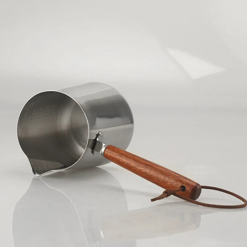 Stainless steel coffee milk jug with a scaled wooden handle shown in a simple solid colour.
