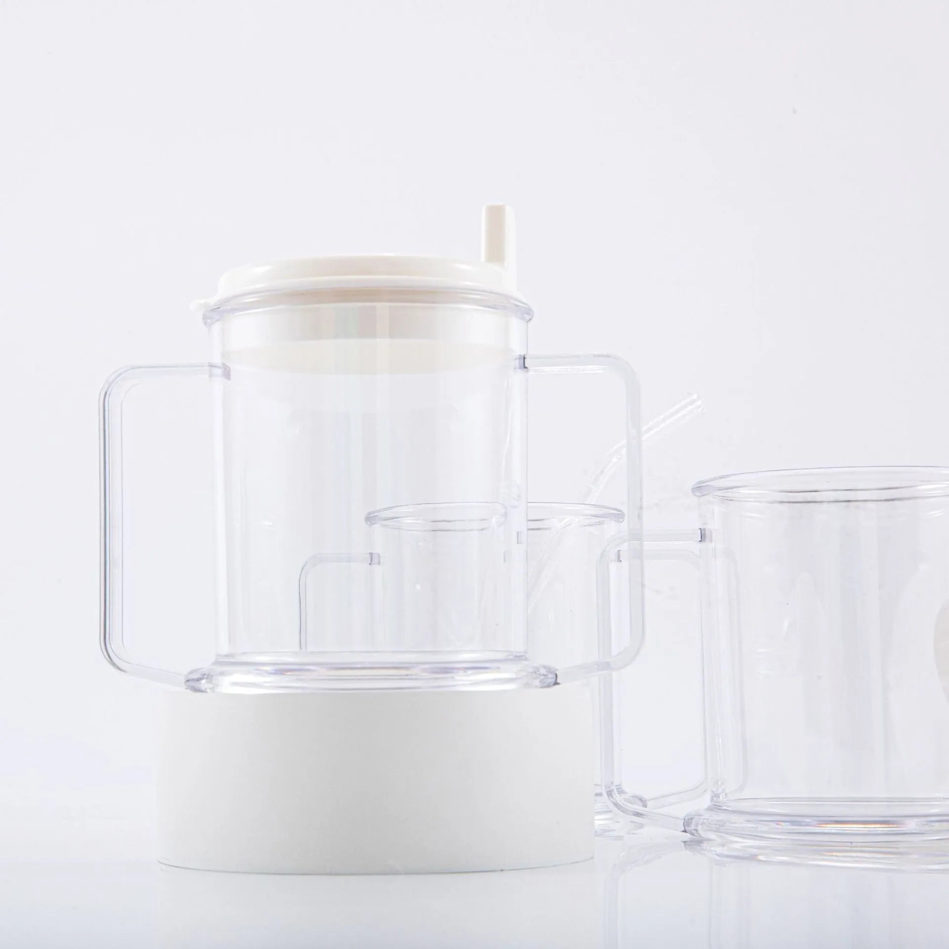 Transparent plastic drinking cup with a grey spill-proof lid on a white background.