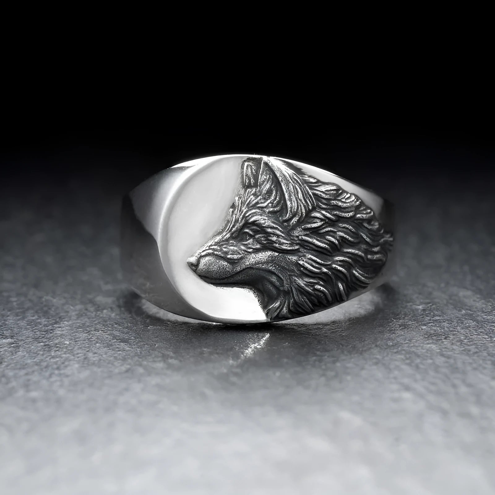 Silver men's ring with a geometric wolf design on a black background.