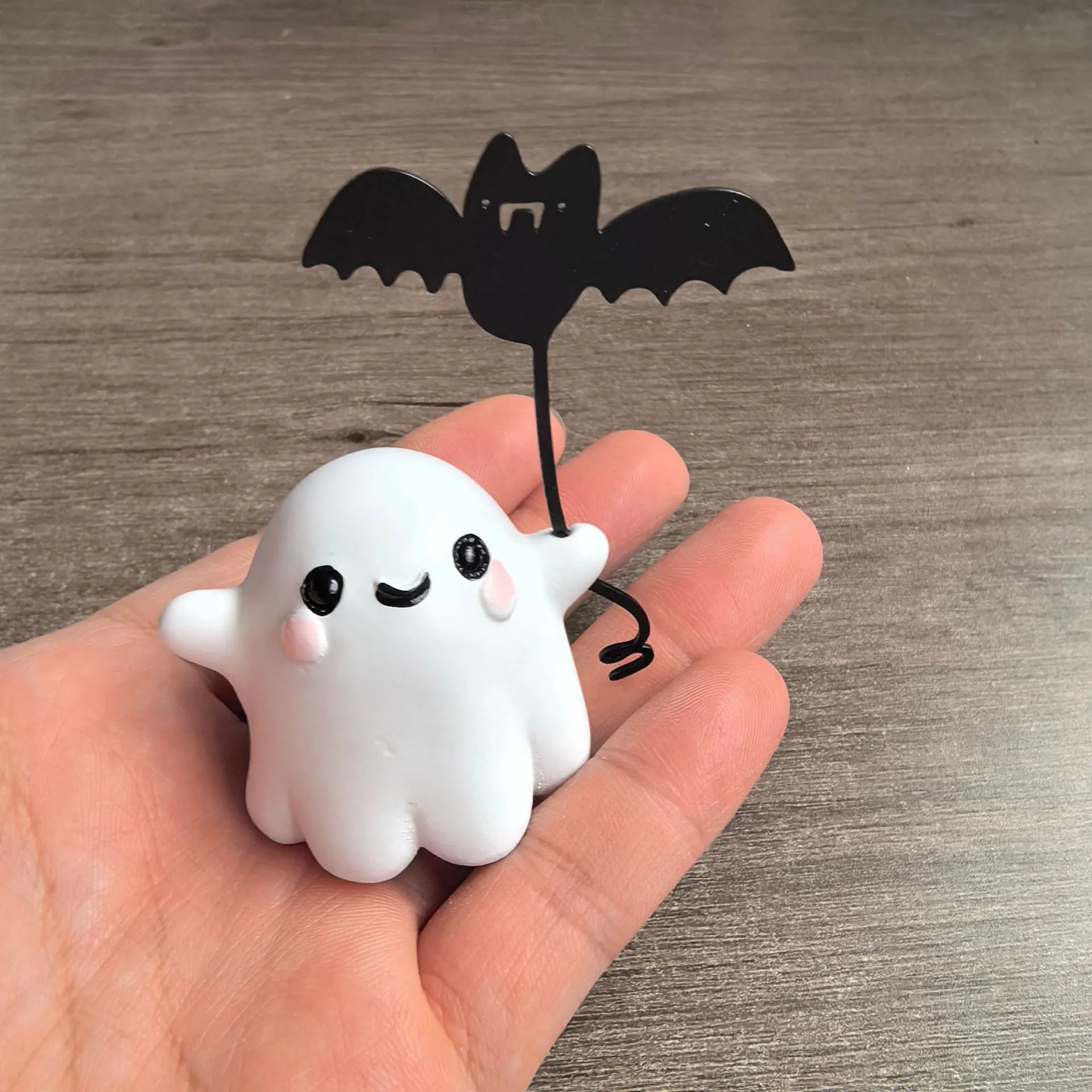 Miniature ghost walking dog statue holding a bat, a small resin Halloween ornament.