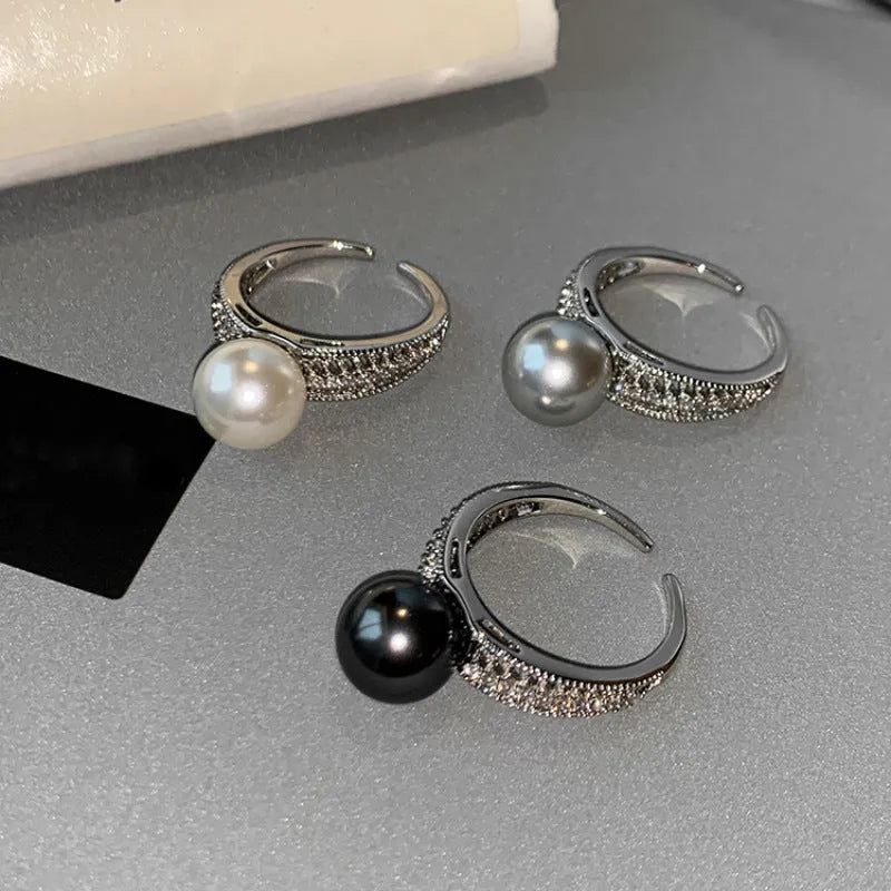 Women's adjustable copper ring with black pearl and geometric open design on an index finger.