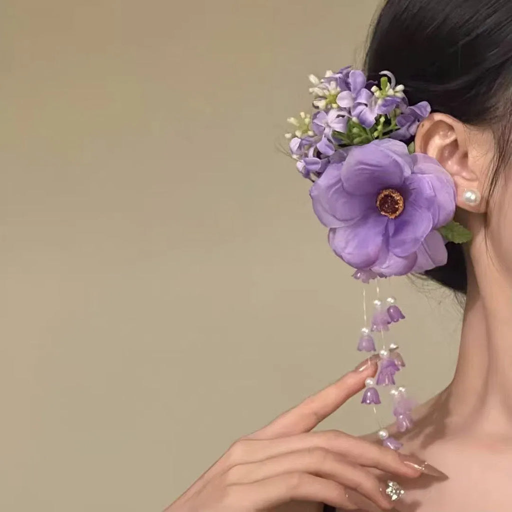 Yellow flower tassel side clip hair accessory for women on a purple background.
