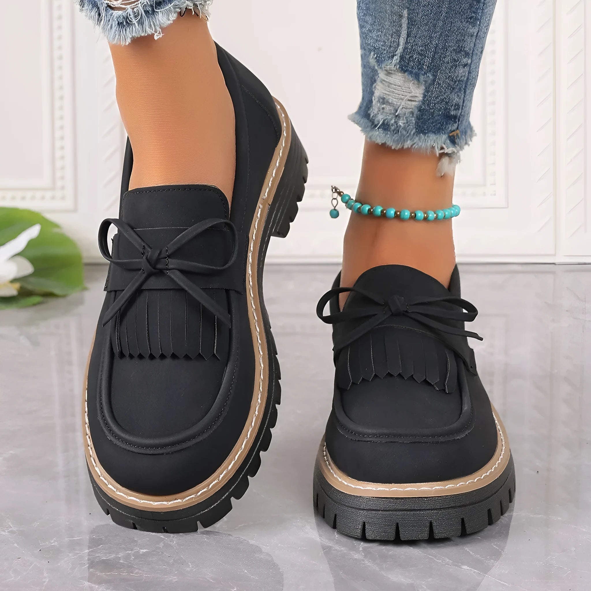 Black women's loafers with a tassel and bowknot decoration on the front, showing a round toe and low-top design.