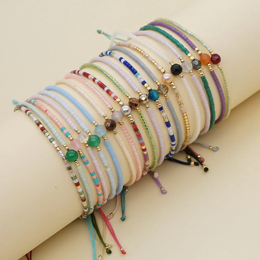 Close-up of a woman's handmade Bohemian bracelet with colourful geometric glass and glaze beads.