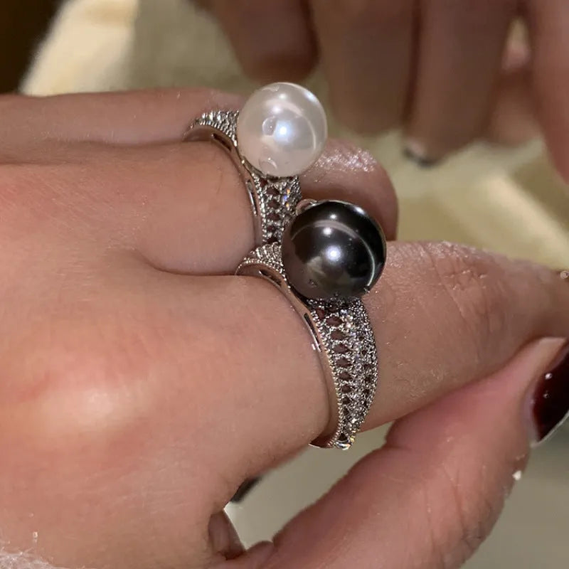 Women's adjustable copper ring with black pearl and geometric open design on an index finger.