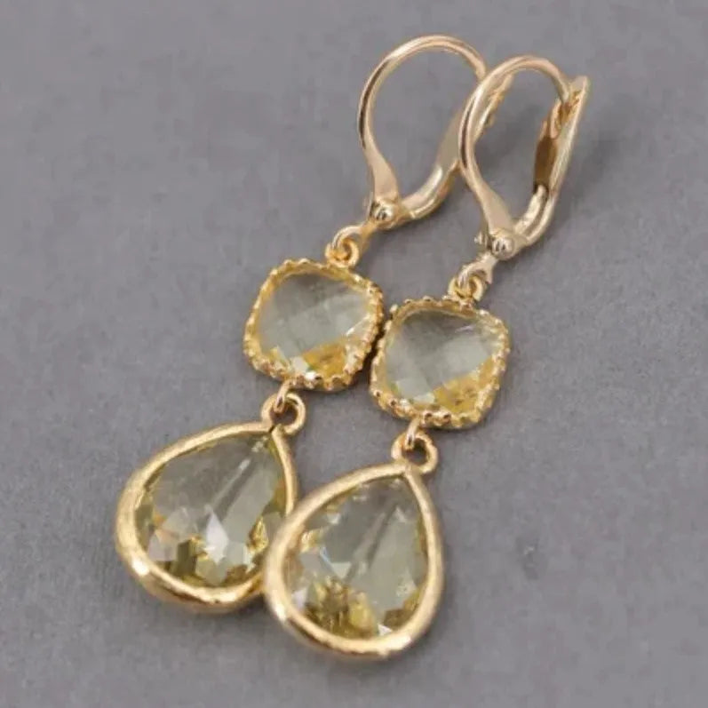 Gold geometric fringe earrings with water droplet design elements on white background