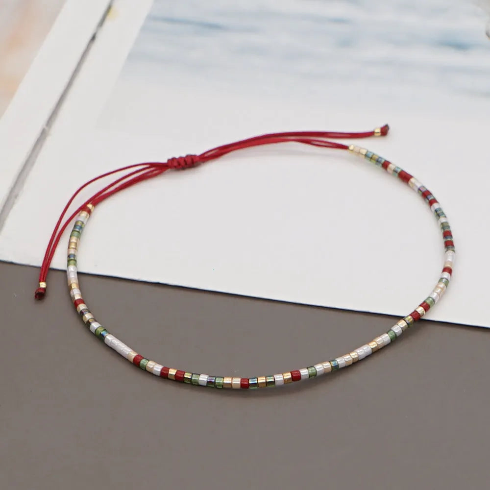Close-up of a woman's handmade Bohemian bracelet with colourful geometric glass and glaze beads.
