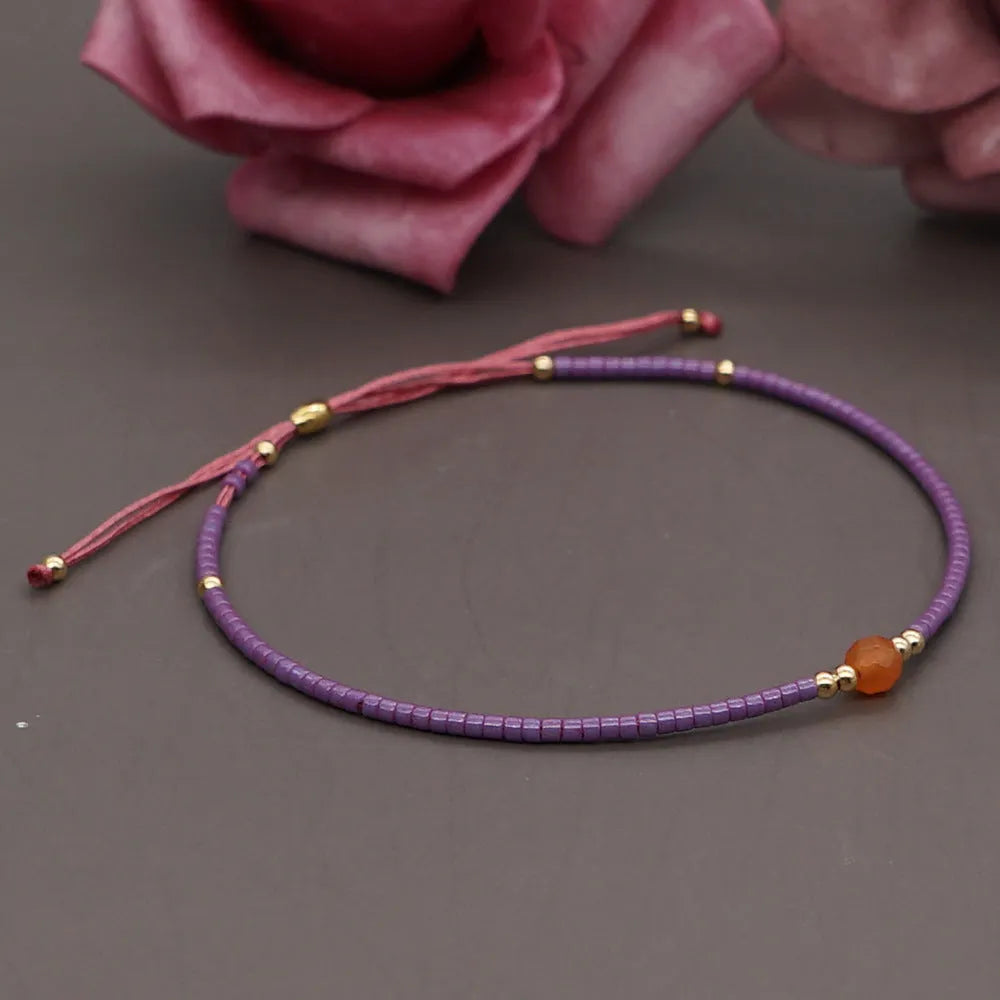 Close-up of a woman's handmade Bohemian bracelet with colourful geometric glass and glaze beads.