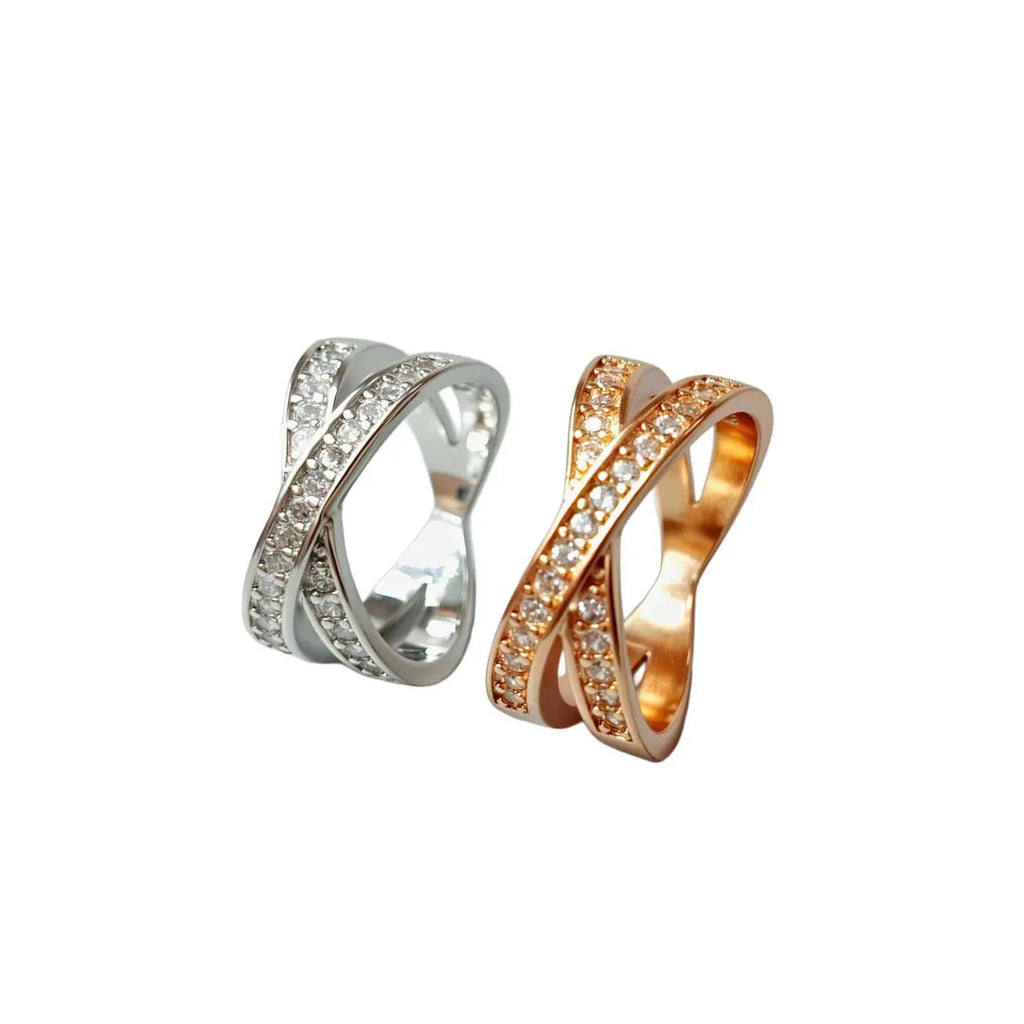 Silver or rose gold metal cross ring with micro-inlaid zircon accents on a plain background.