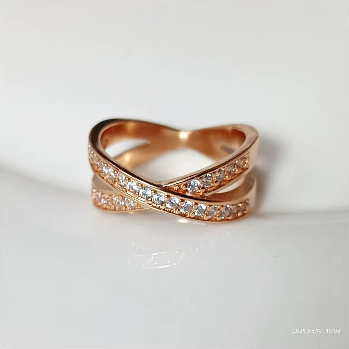 Silver or rose gold metal cross ring with micro-inlaid zircon accents on a plain background.