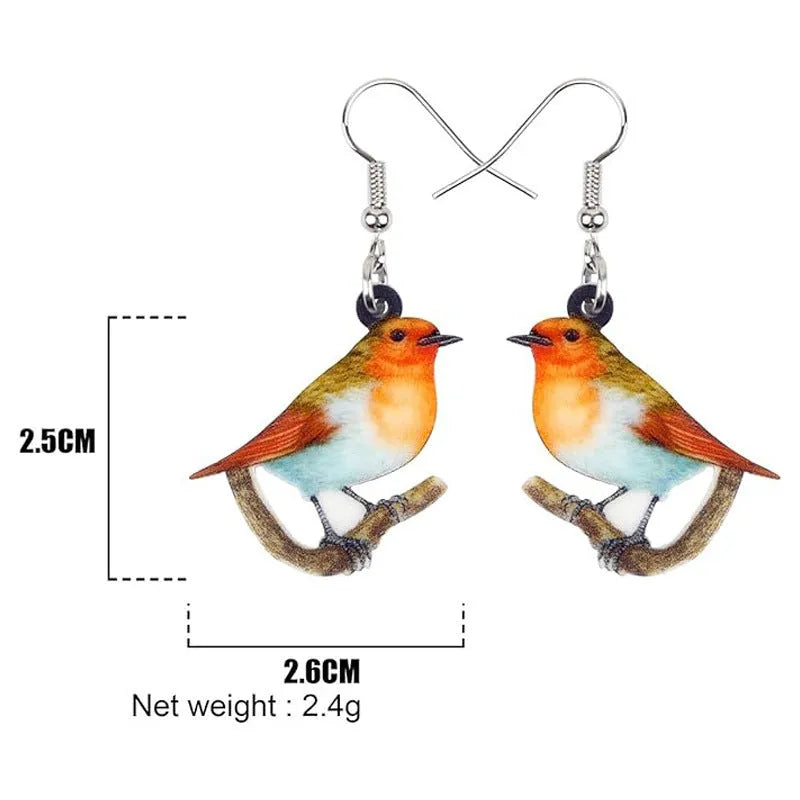 Close-up of blue titmouse and geometric zodiac pendant earrings made from printed acrylic.