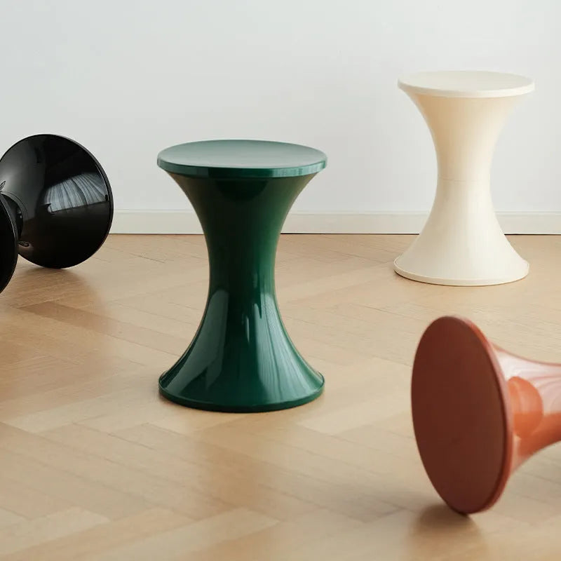 A white hourglass-shaped plastic shoe changing stool on a wooden floor.