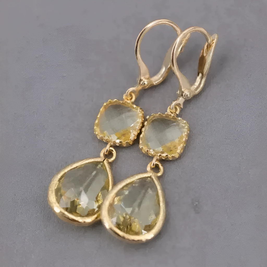Gold geometric fringe earrings with water droplet design elements on white background