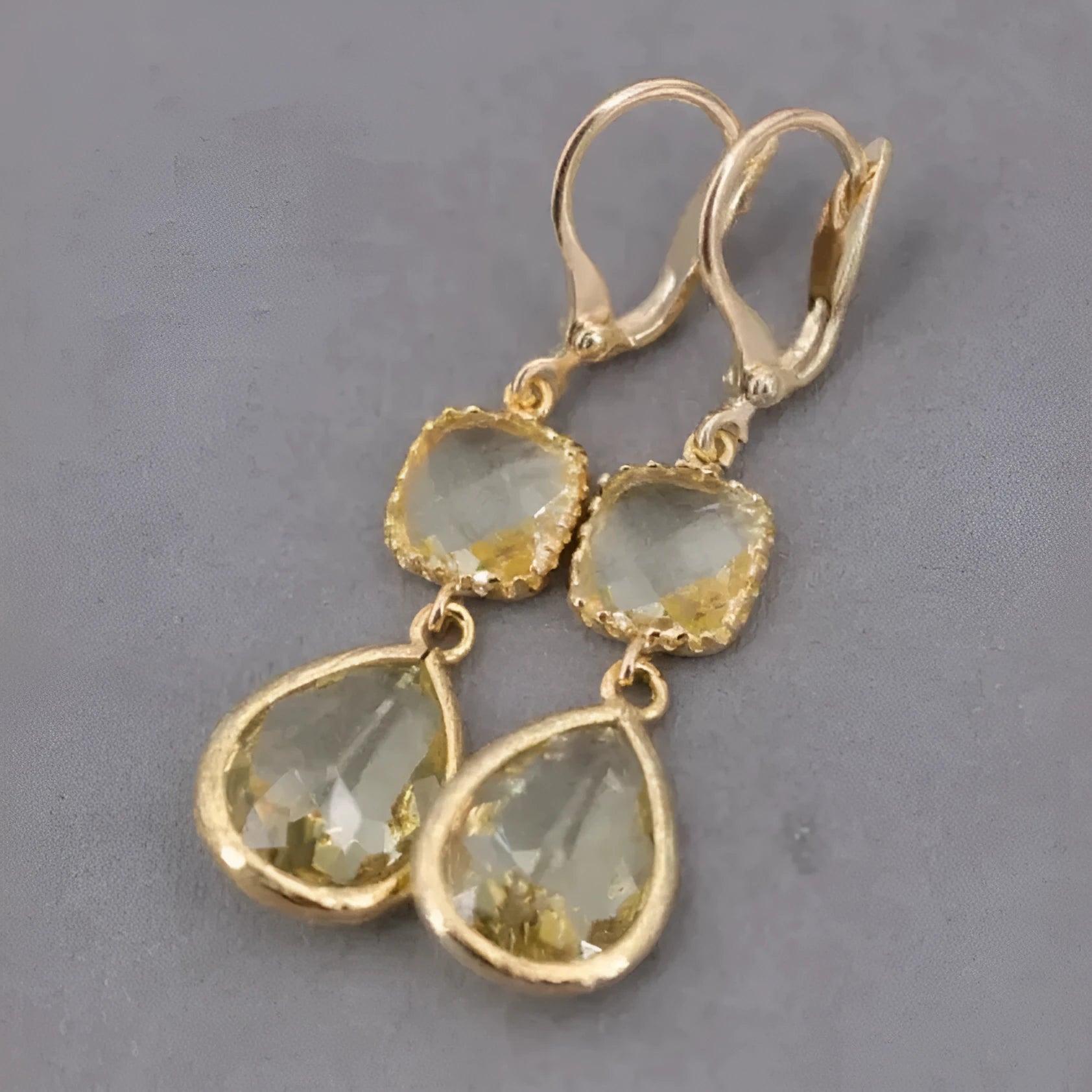 Gold geometric fringe earrings with water droplet design elements on white background