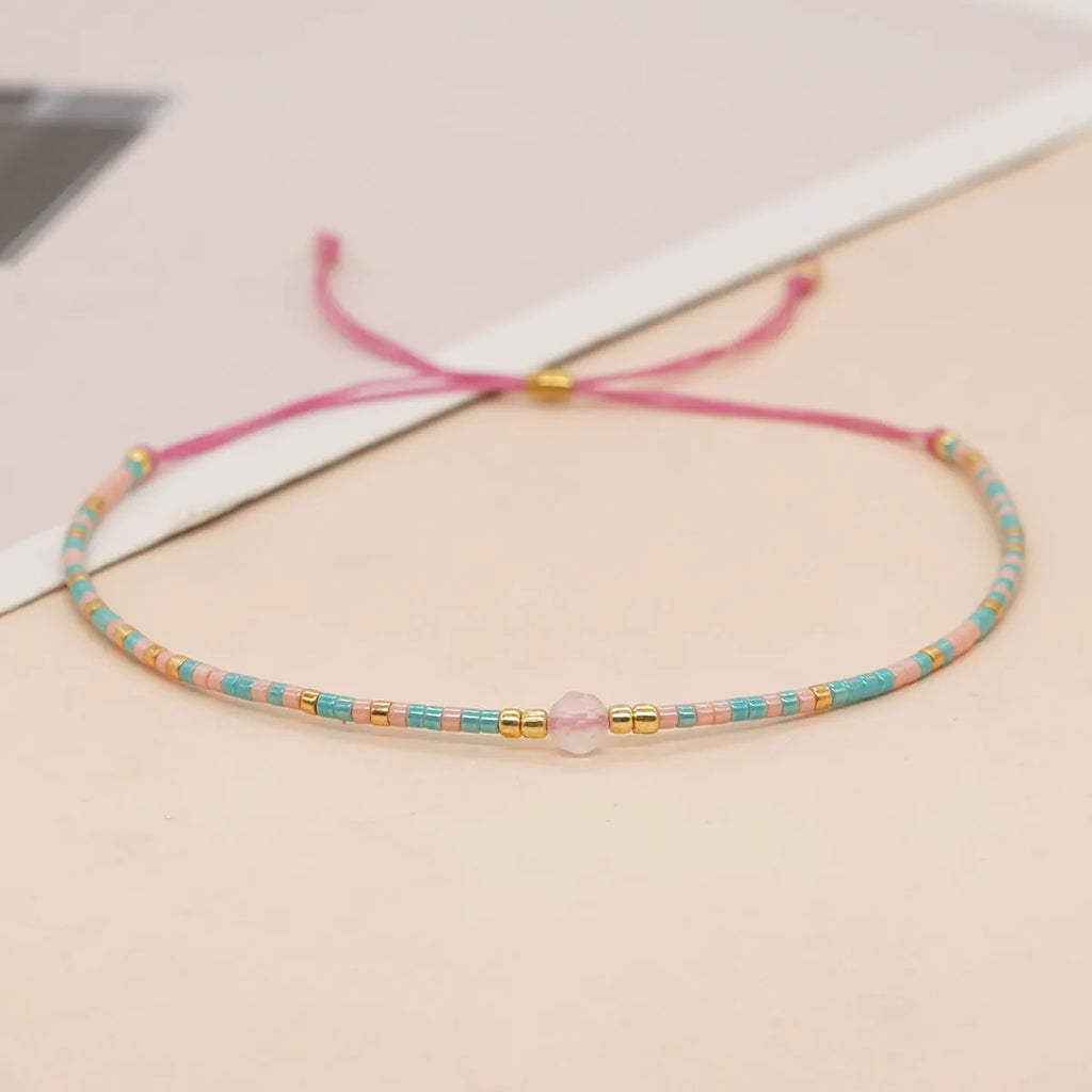 Close-up of a woman's handmade Bohemian bracelet with colourful geometric glass and glaze beads.