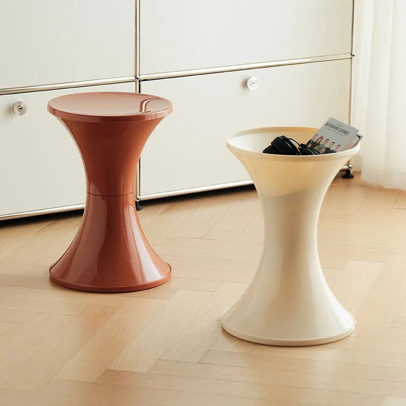 A white hourglass-shaped plastic shoe changing stool on a wooden floor.