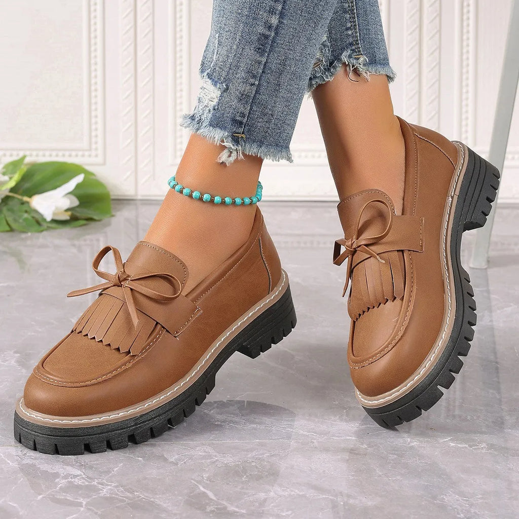 Black women's loafers with a tassel and bowknot decoration on the front, showing a round toe and low-top design.