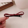 Wine red leather bow hair barrette on a white background.