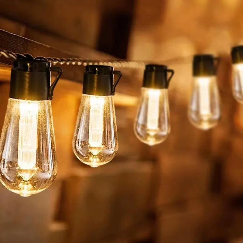 Retro infusion bottle shaped solar outdoor string lights draped in a garden setting.