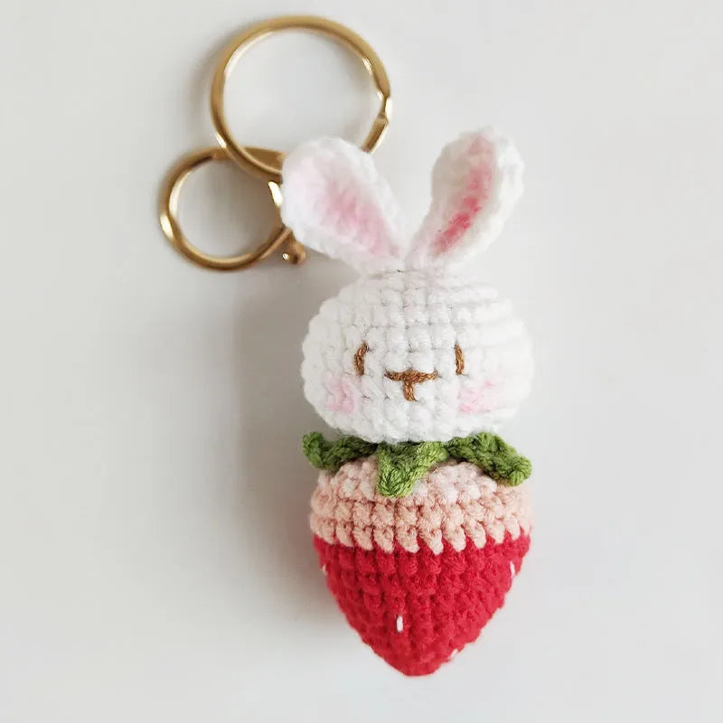 Close-up of a white hand-woven wire rabbit keychain pendant with a strawberry pattern detail.