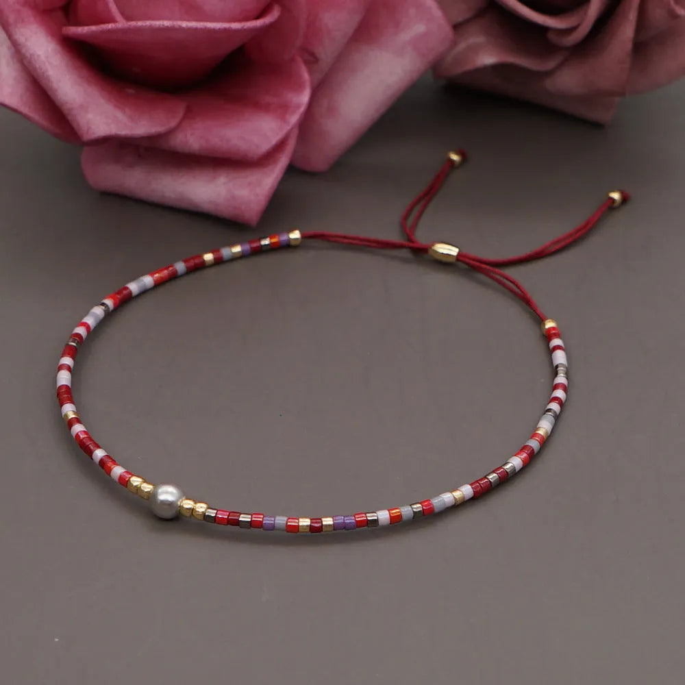 Close-up of a woman's handmade Bohemian bracelet with colourful geometric glass and glaze beads.