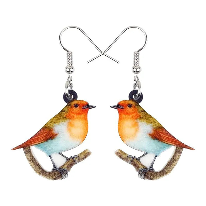 Close-up of blue titmouse and geometric zodiac pendant earrings made from printed acrylic.