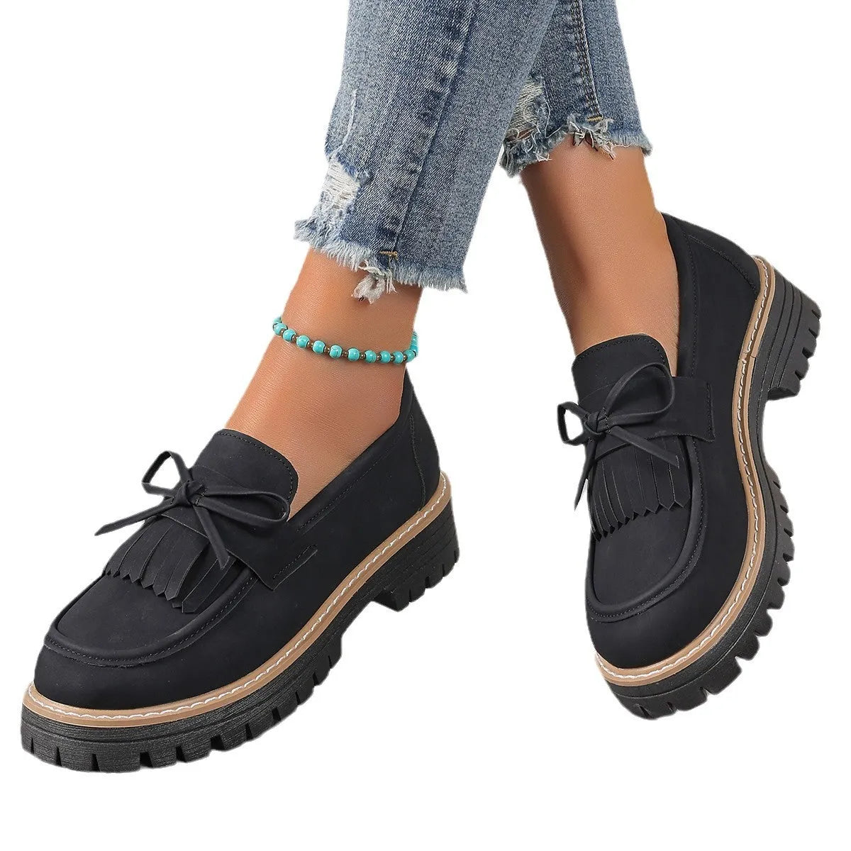 Black women's loafers with a tassel and bowknot decoration on the front, showing a round toe and low-top design.