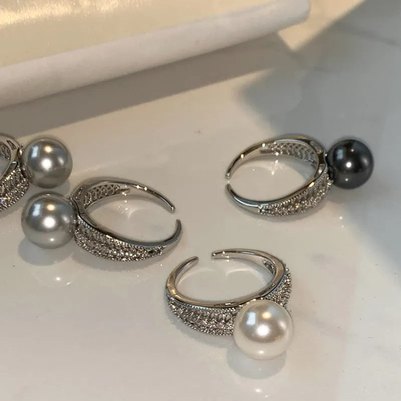 Women's adjustable copper ring with black pearl and geometric open design on an index finger.