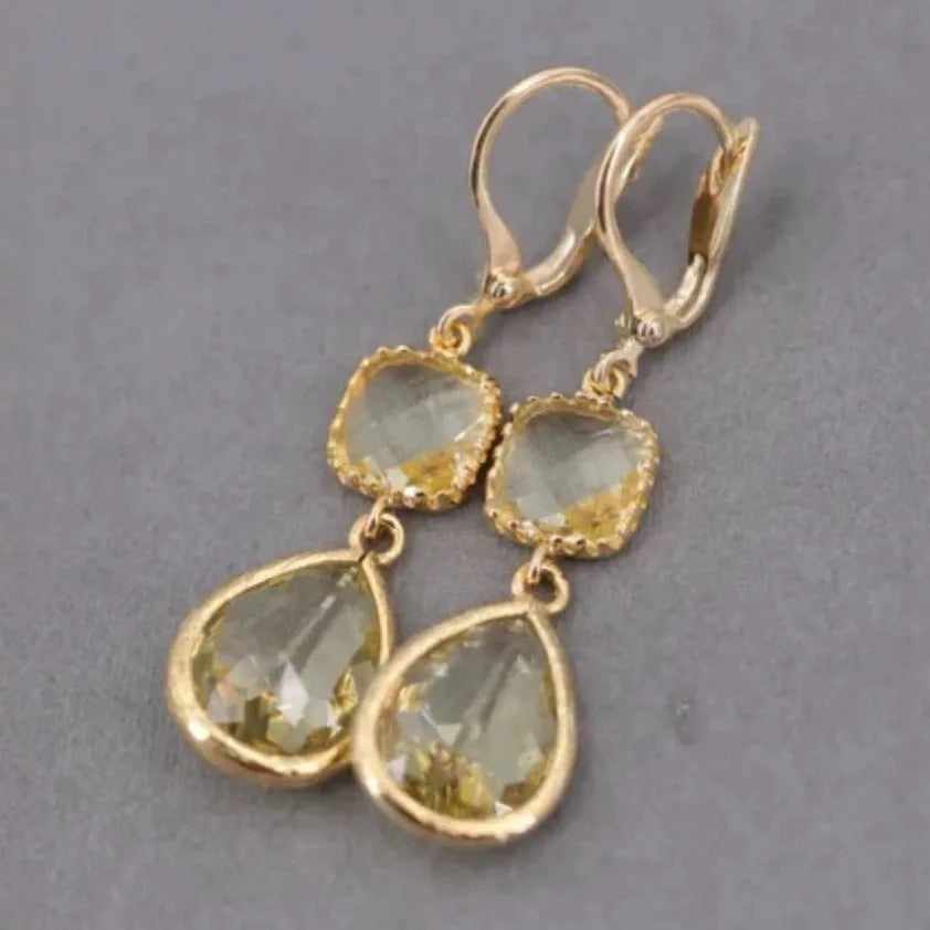Gold geometric fringe earrings with water droplet design elements on white background