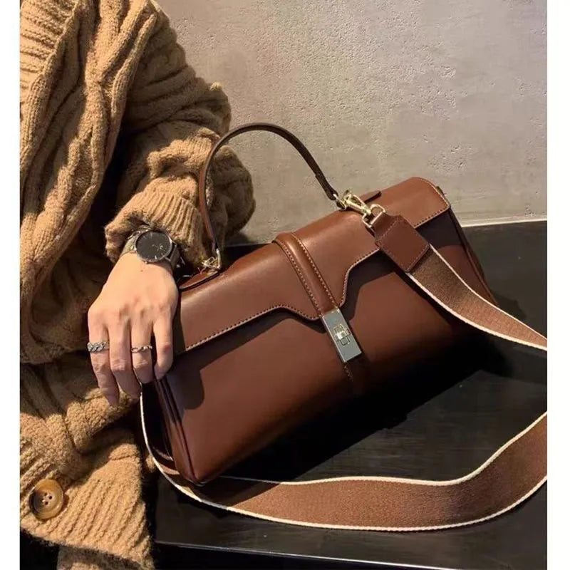 Women's cylindrical leather messenger bag in black with internal organiser pockets