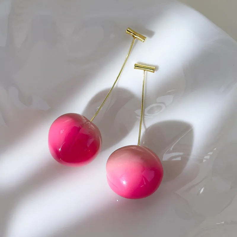 A pair of coloured acrylic peach fruit earrings on copper posts, shown in small and large size options.