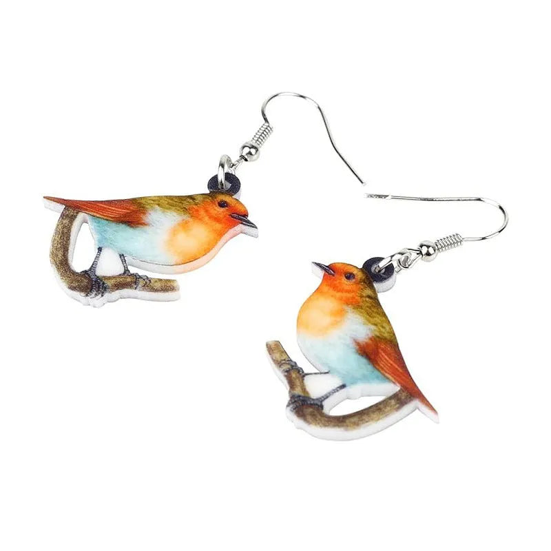 Close-up of blue titmouse and geometric zodiac pendant earrings made from printed acrylic.